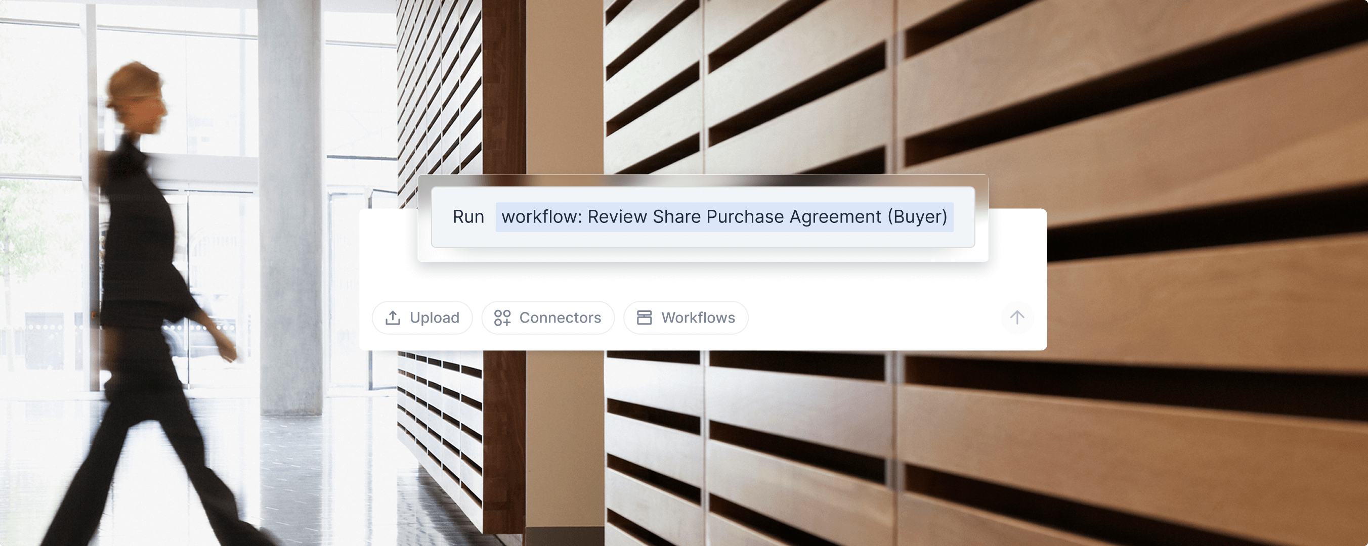 User interface showing the command to run workflow: Review Share Purchase Agreement (Buyer), with buttons for Upload, Connectors, and Workflows in the background of a walking person in a modern office.