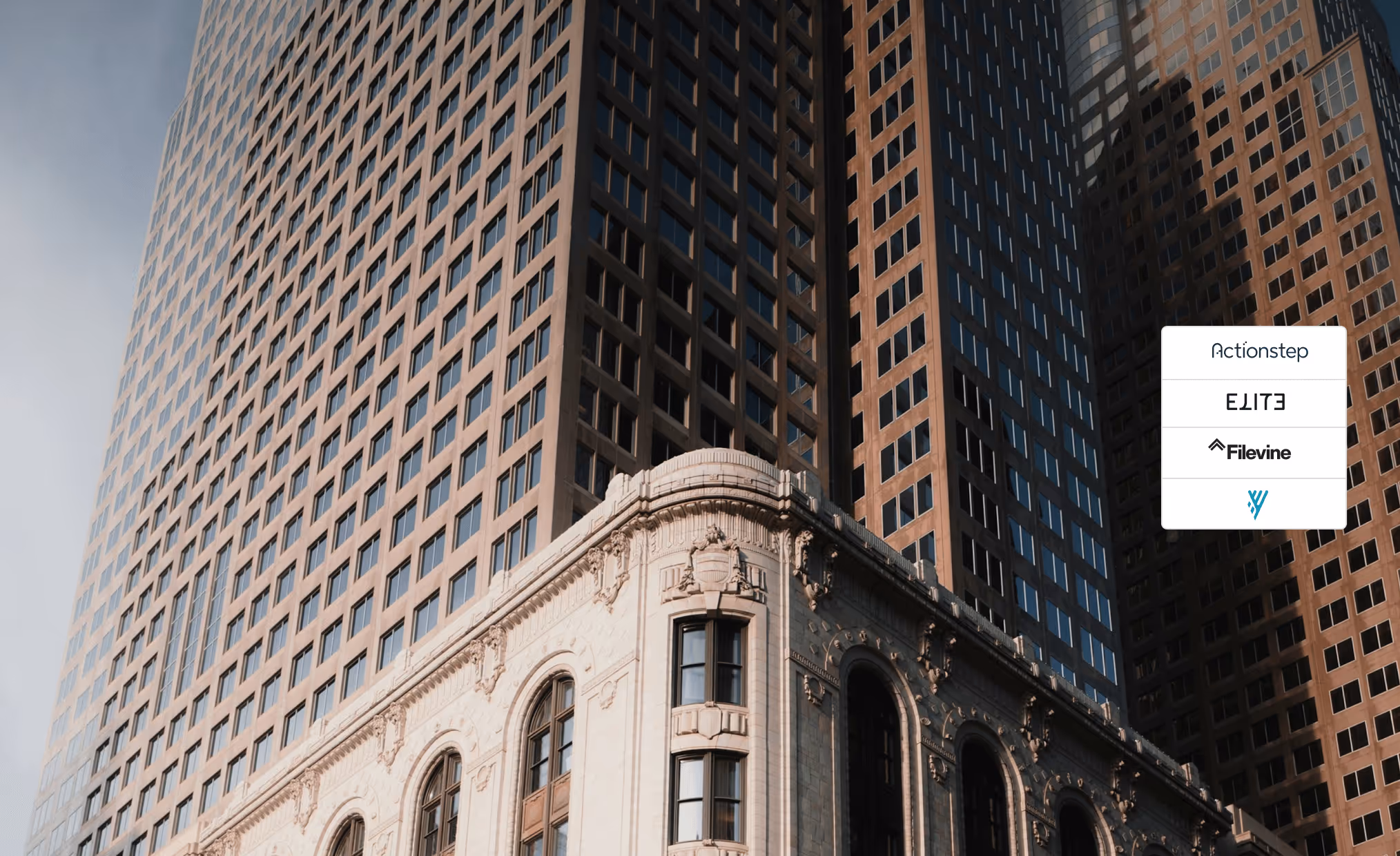 Corner of a decorative classic building in front of tall modern glass skyscrapers under a clear sky.