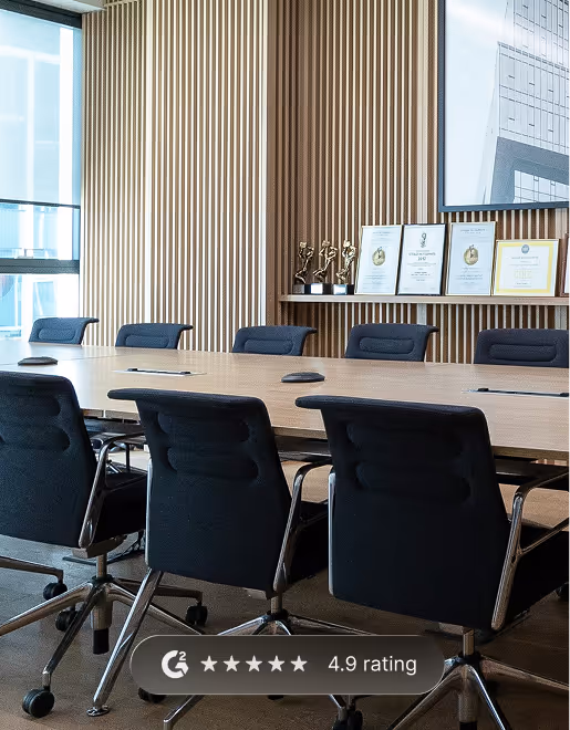 Modern conference room with black chairs around a wooden table and framed awards on a wooden slat wall.