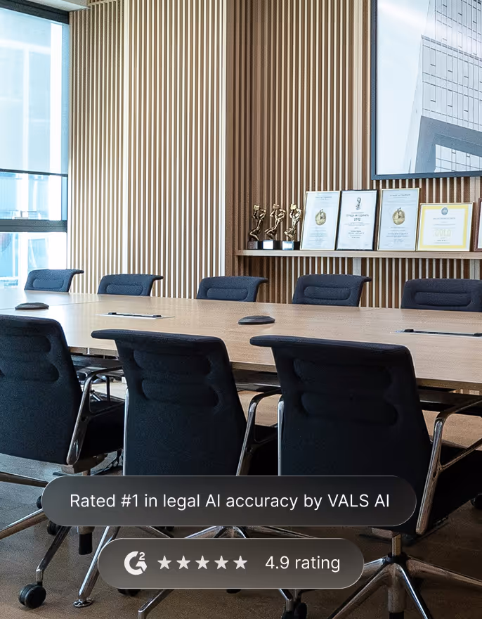 Modern conference room with black chairs around a wooden table and framed awards on a wooden slat wall.