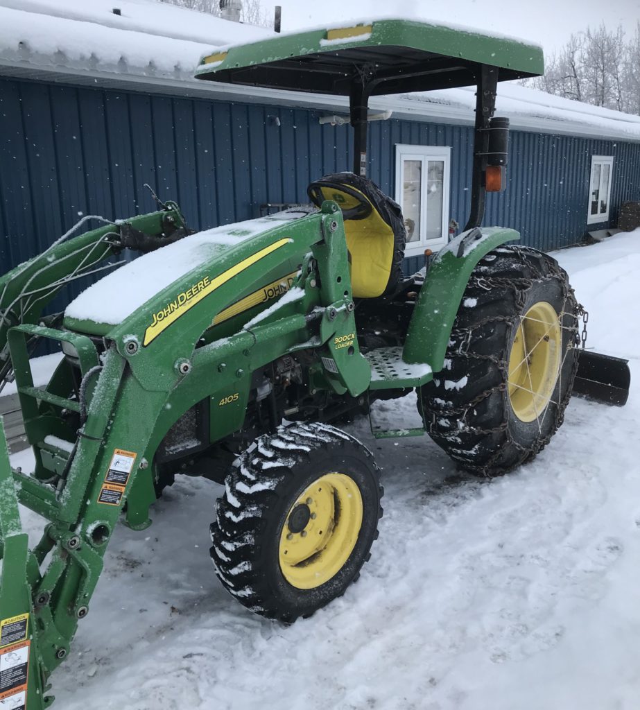 green and yellow tractor used to plow snow