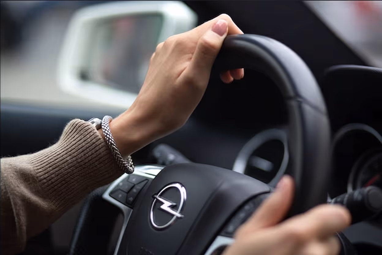Mains féminines tenant un volant d'Opel à l'intérieur d'une voiture.