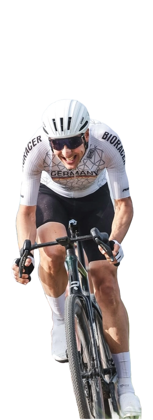 Radrennfahrer in weißem Helm und Trikot mit der Aufschrift Deutschland fährt auf einem Rennrad.