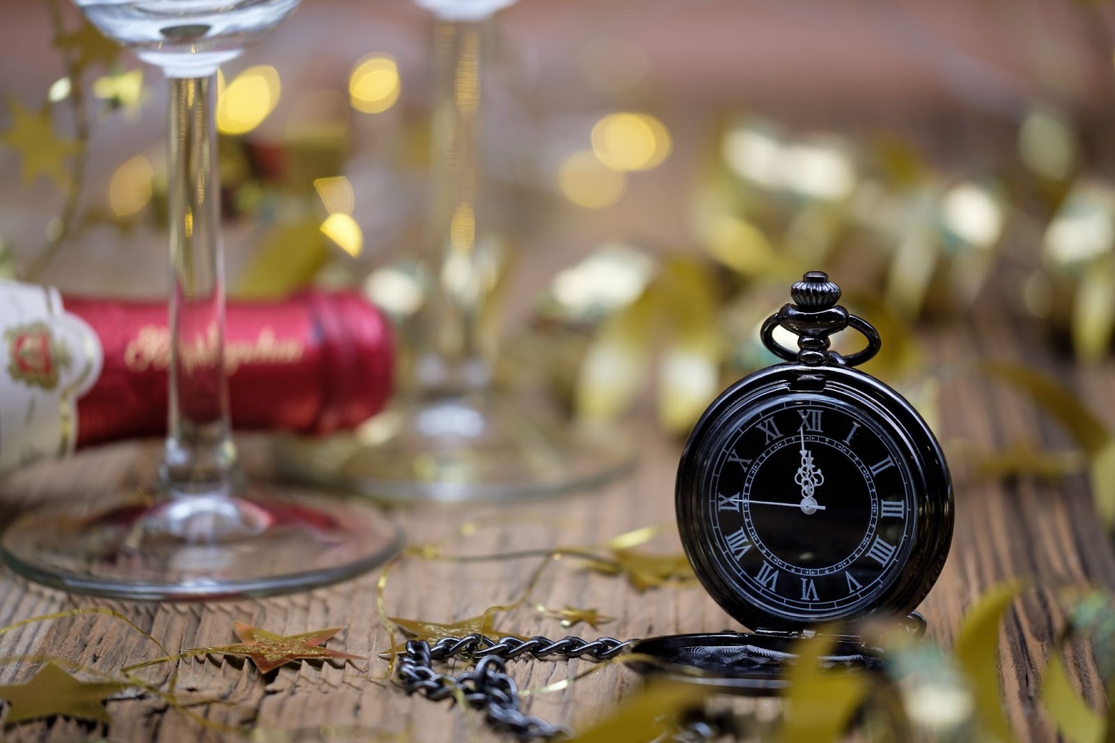 A watch near the wine bottle and glass surrounded by confetti