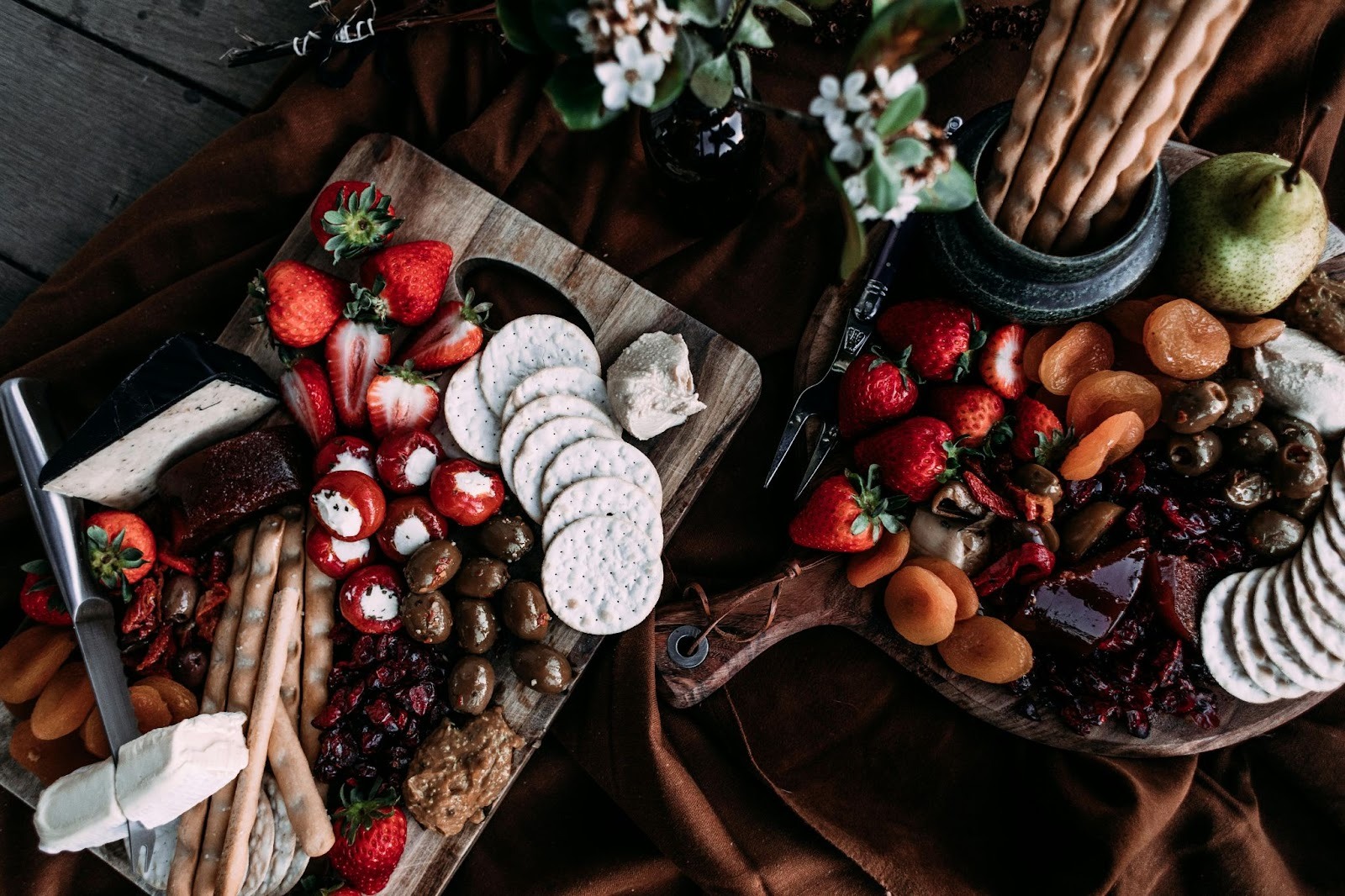 One pizza platter and one chopping board, both full of food and fruits. Knife placed on the chopping board