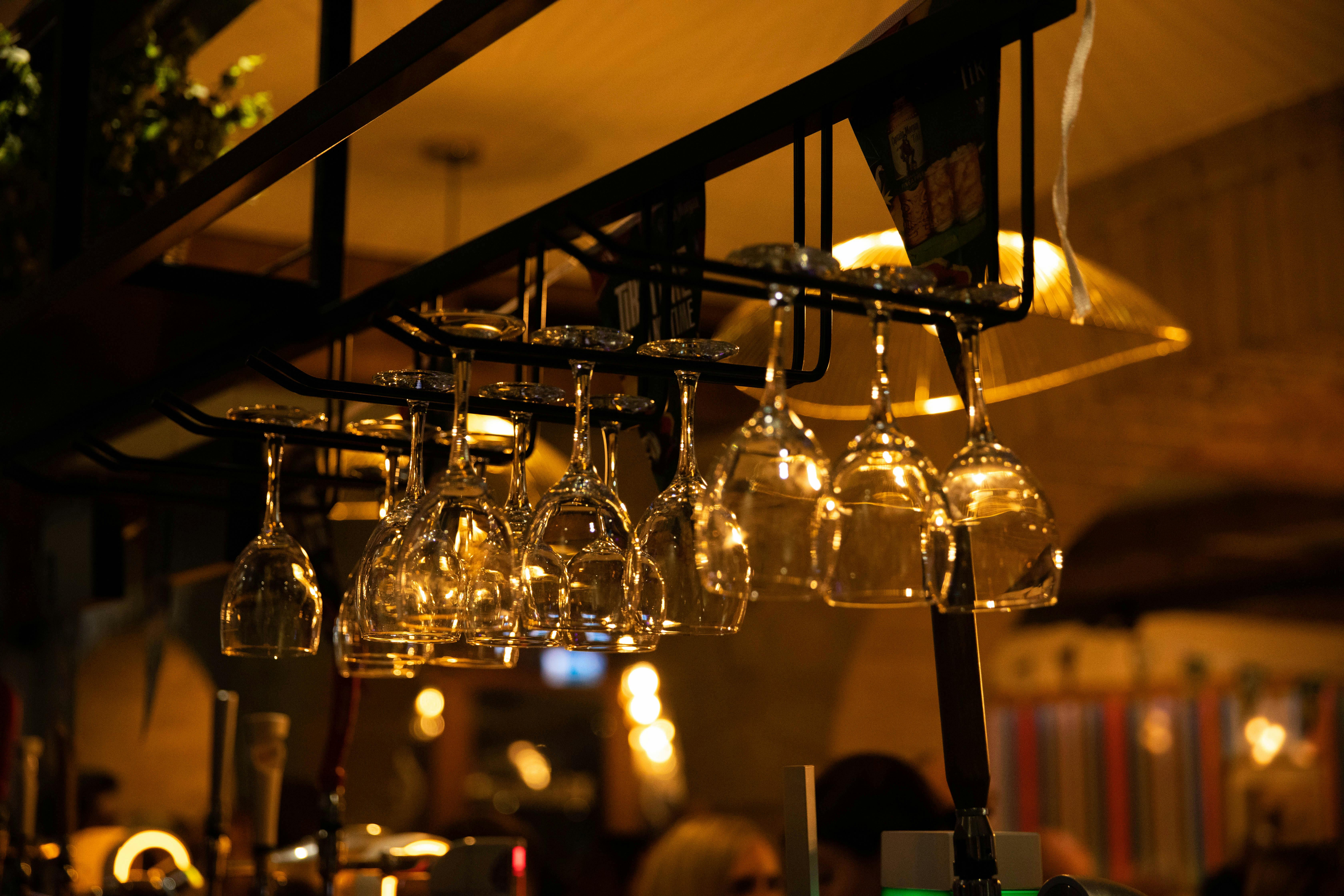 Wine glasses hanging upside down in bar and warm light in background