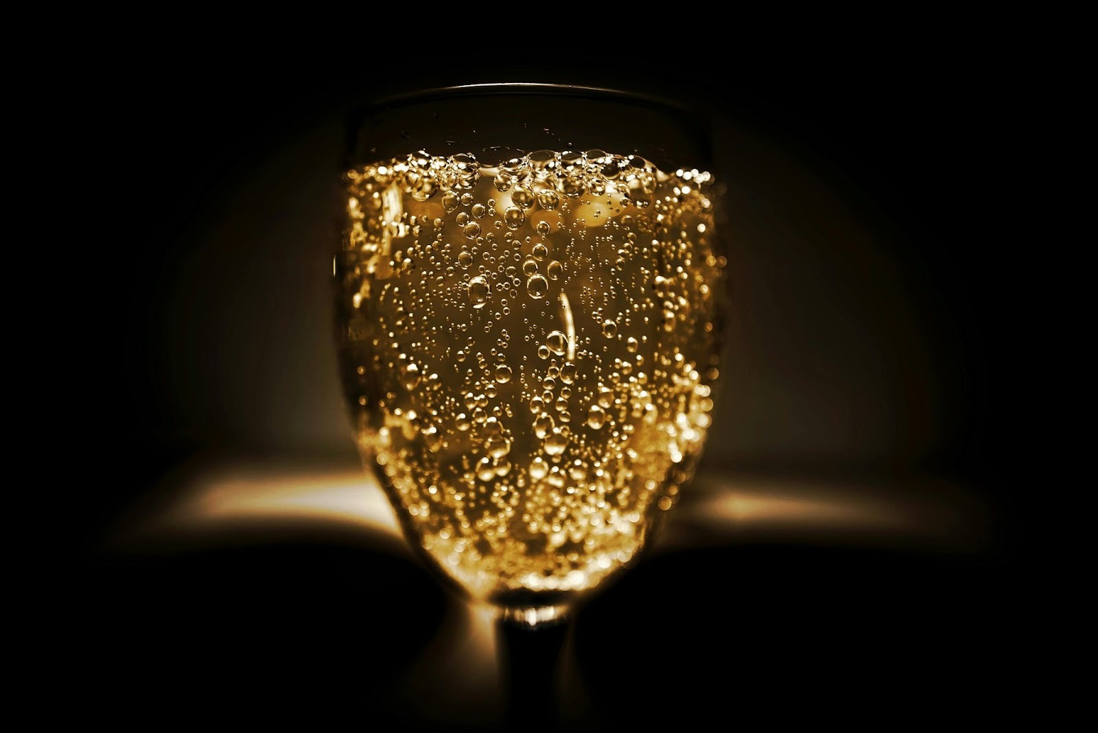 A sparkling wine glass pour in focus with black background