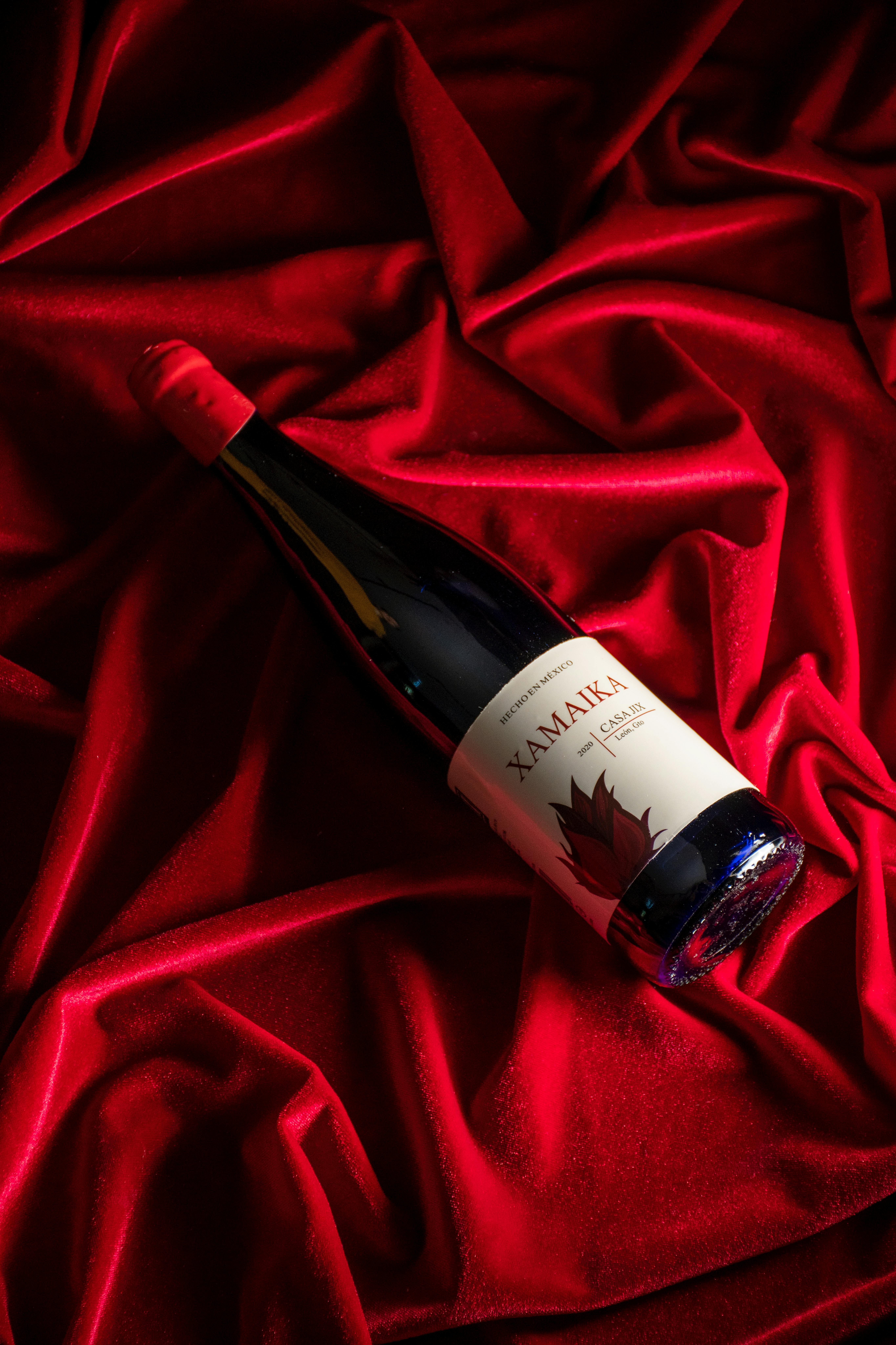 A red wine bottle laying on a velvet red cloth