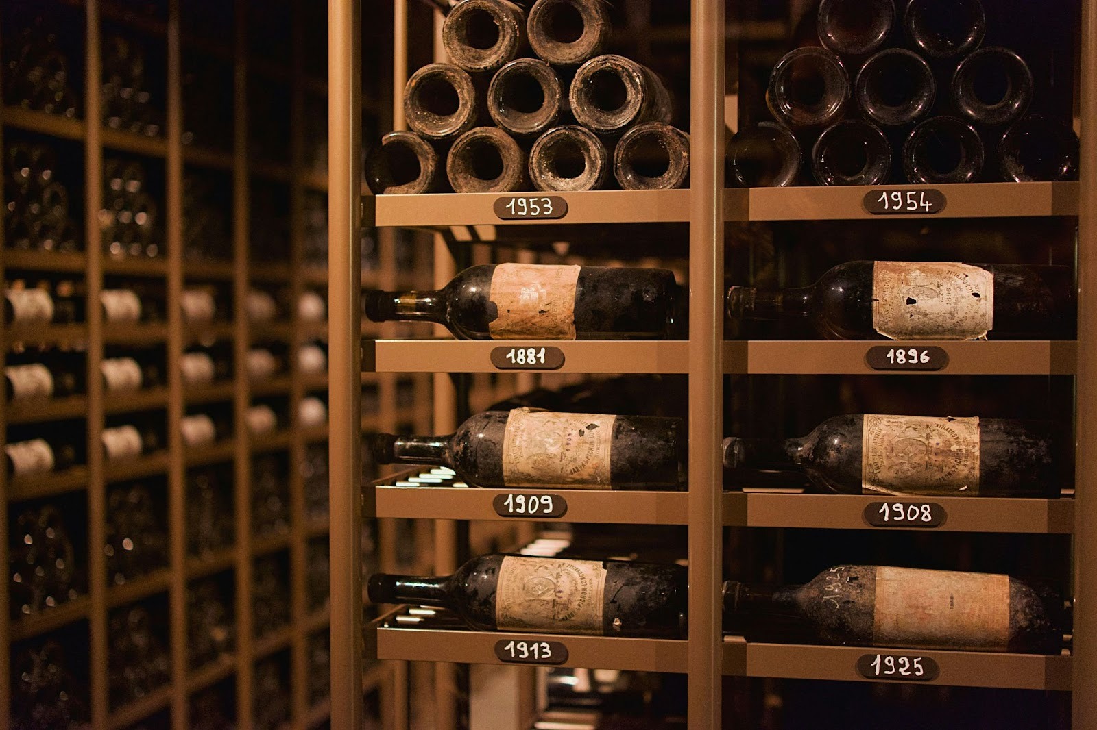 A wine cellar with very old wine bottles from different years stacked in wooden racks