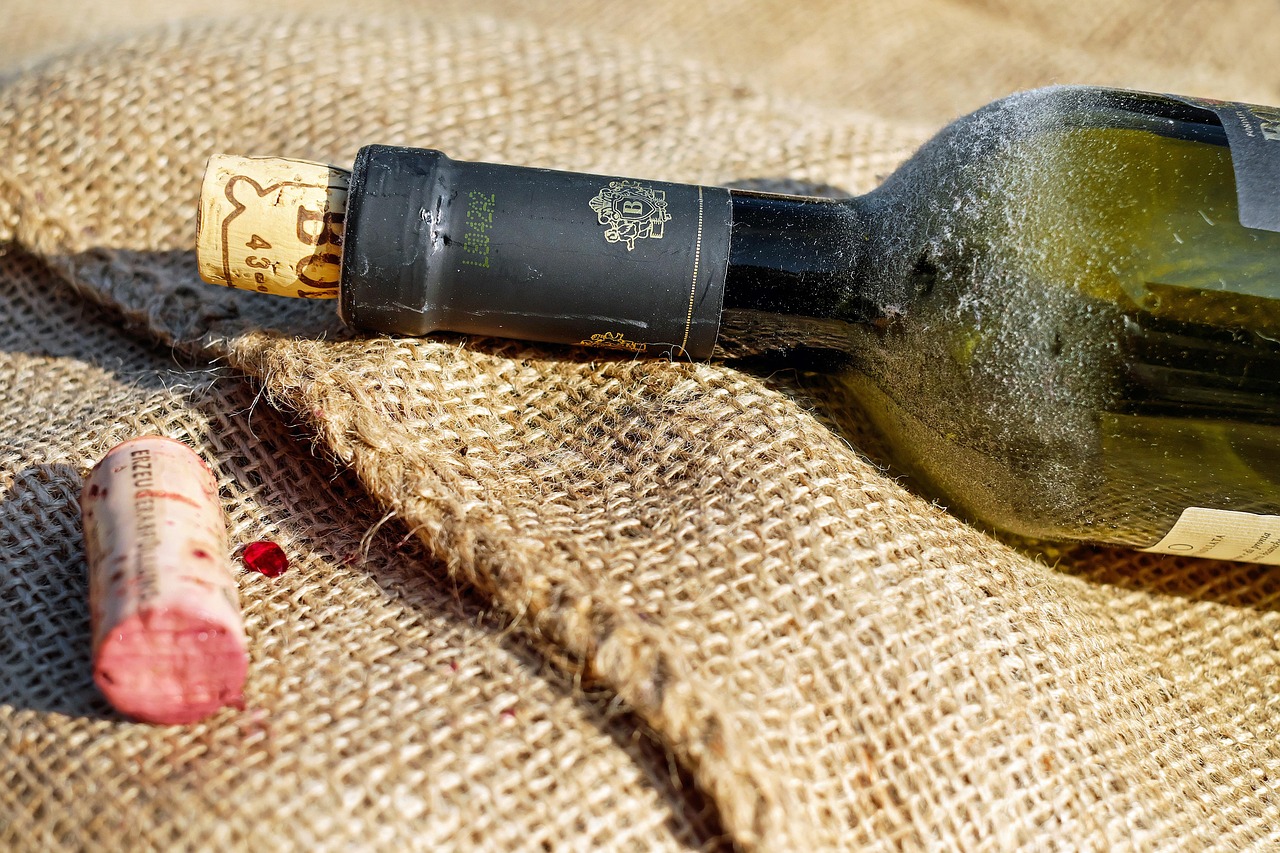 a wine bottle laying on a sack with another cork near it turned red