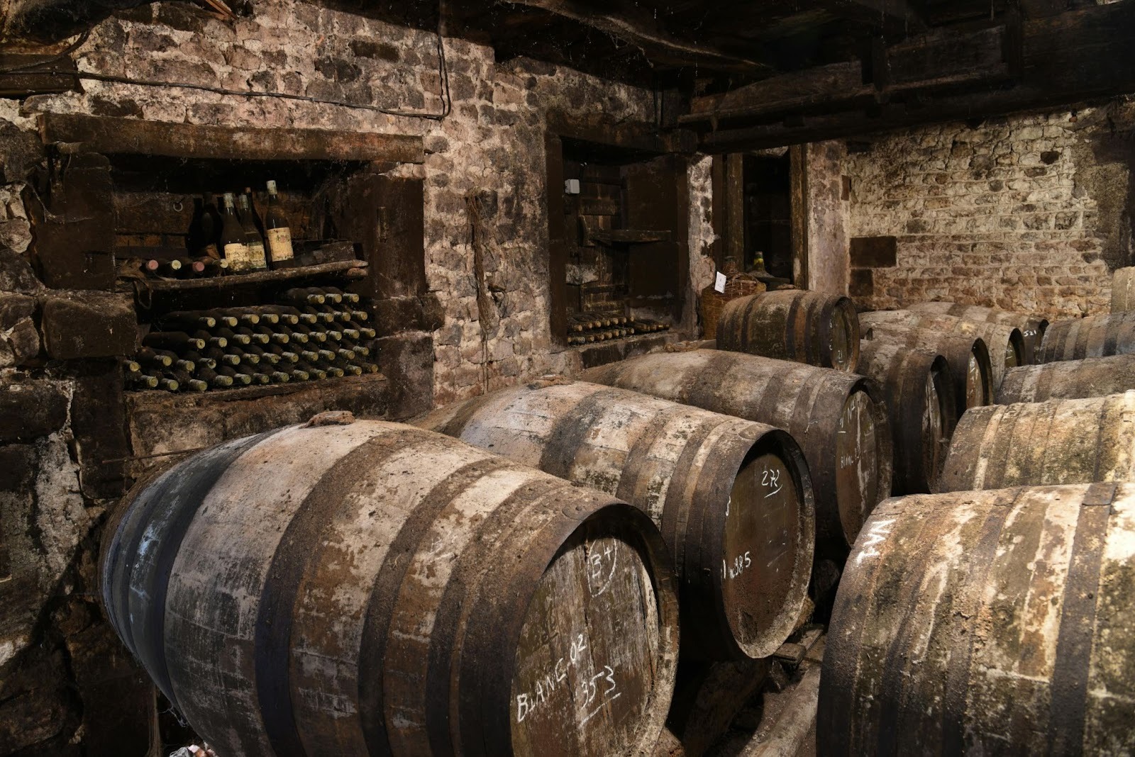 An old wine cellar with old wine bottles stacked in two compartments in the wall
