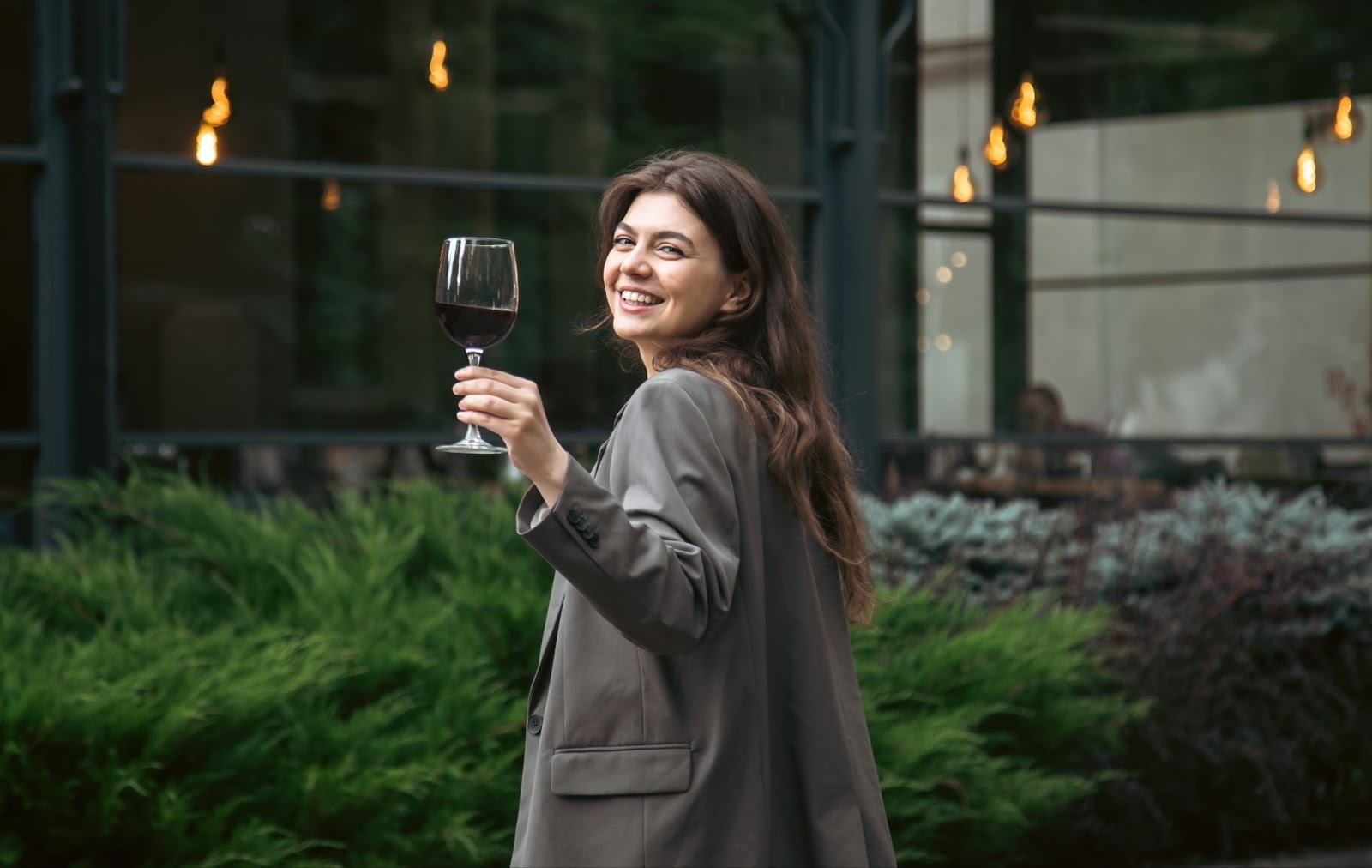 A lady holding her wine glass high turning back towards camera