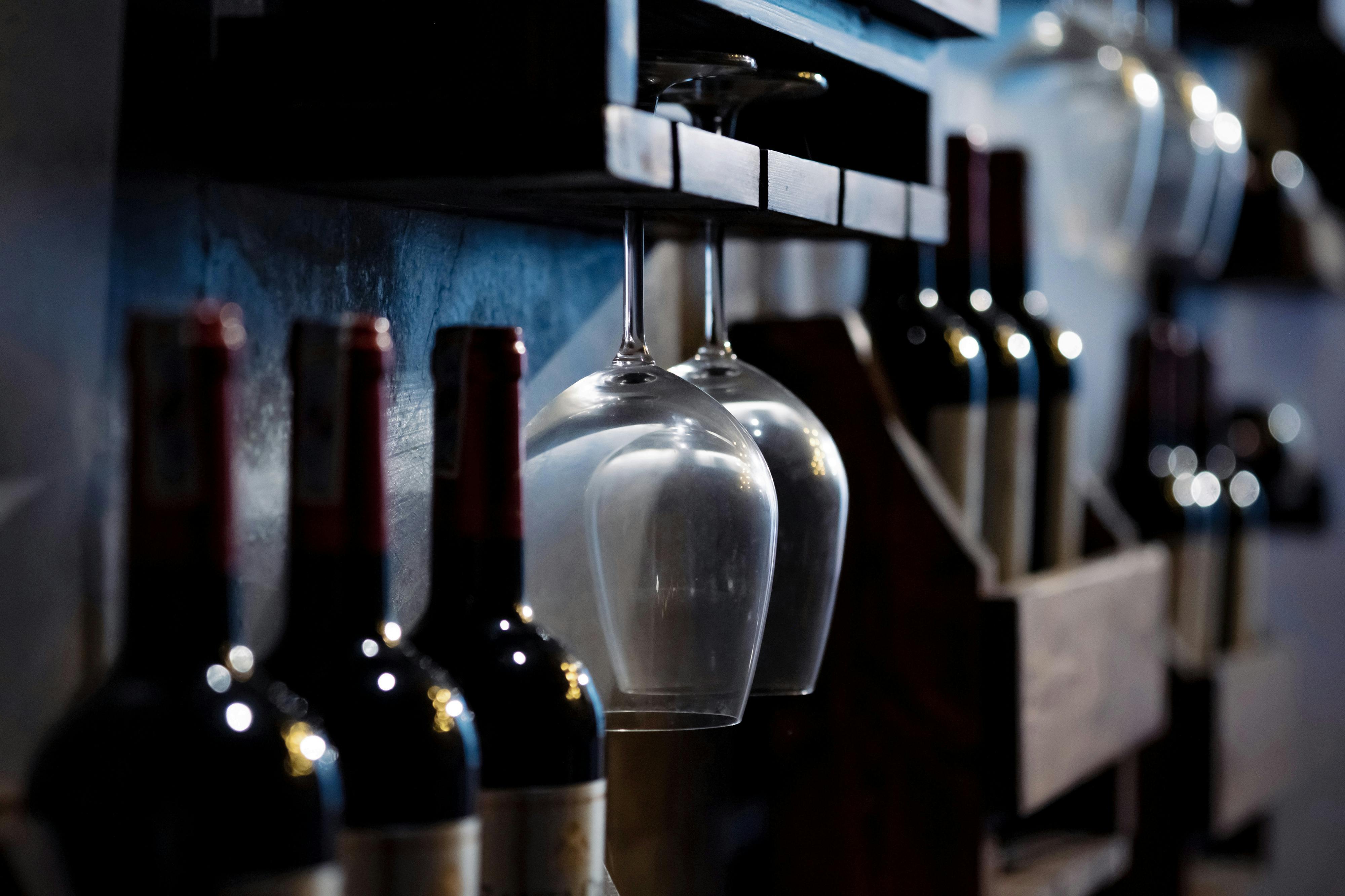 Wine bottles on wooden boxes and two inverted hanging glasses