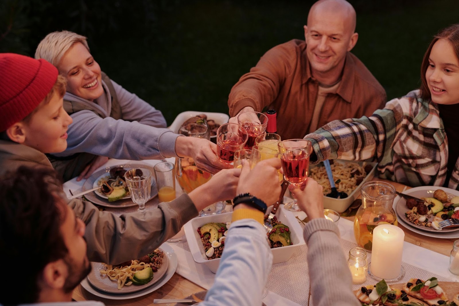 People clinking wine glasses for a toast at dinner table