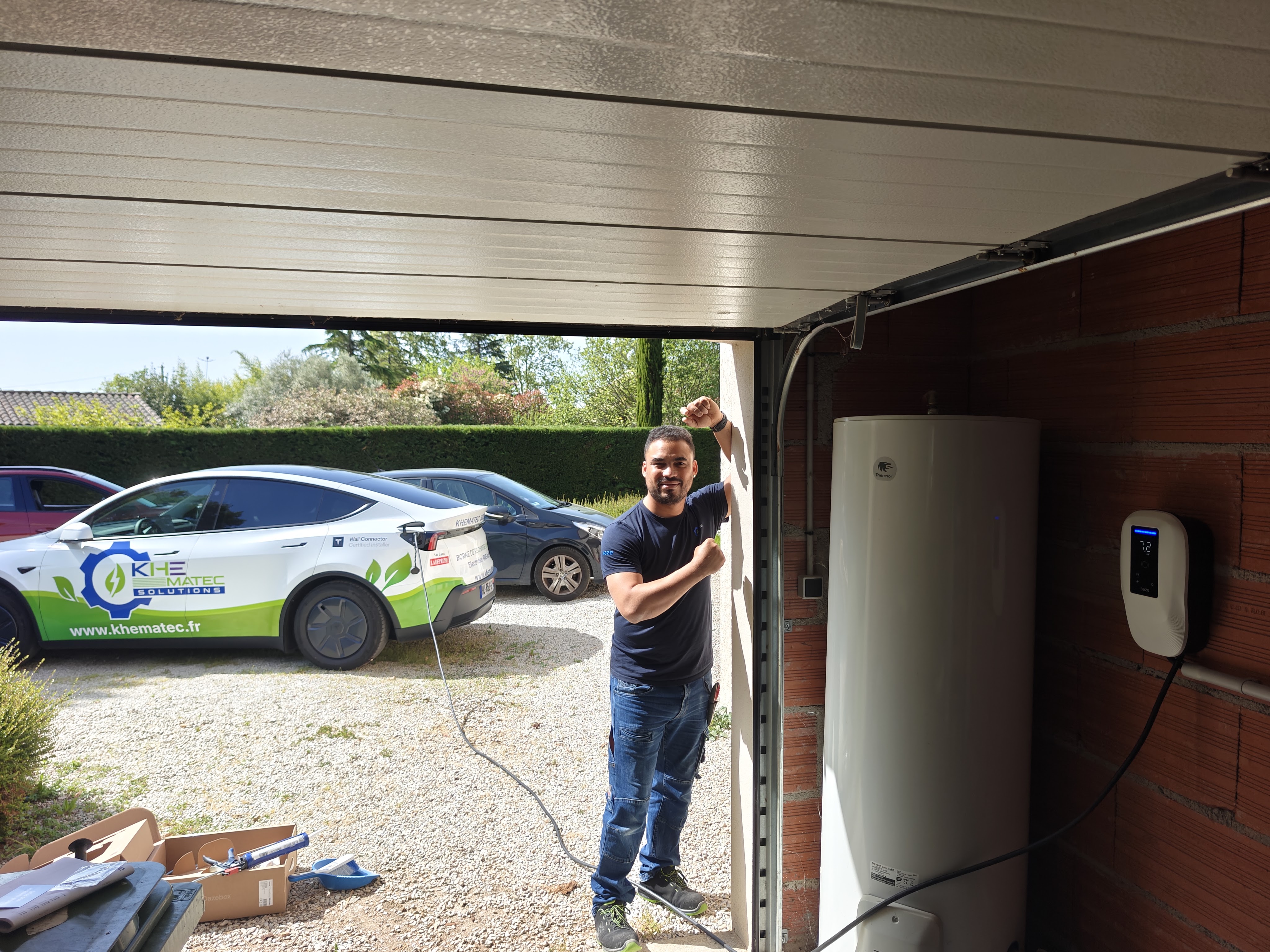 Installation de borne de recharge à Blagnac par Khematec Solutions, artisan devant une borne murale dans un garage.
