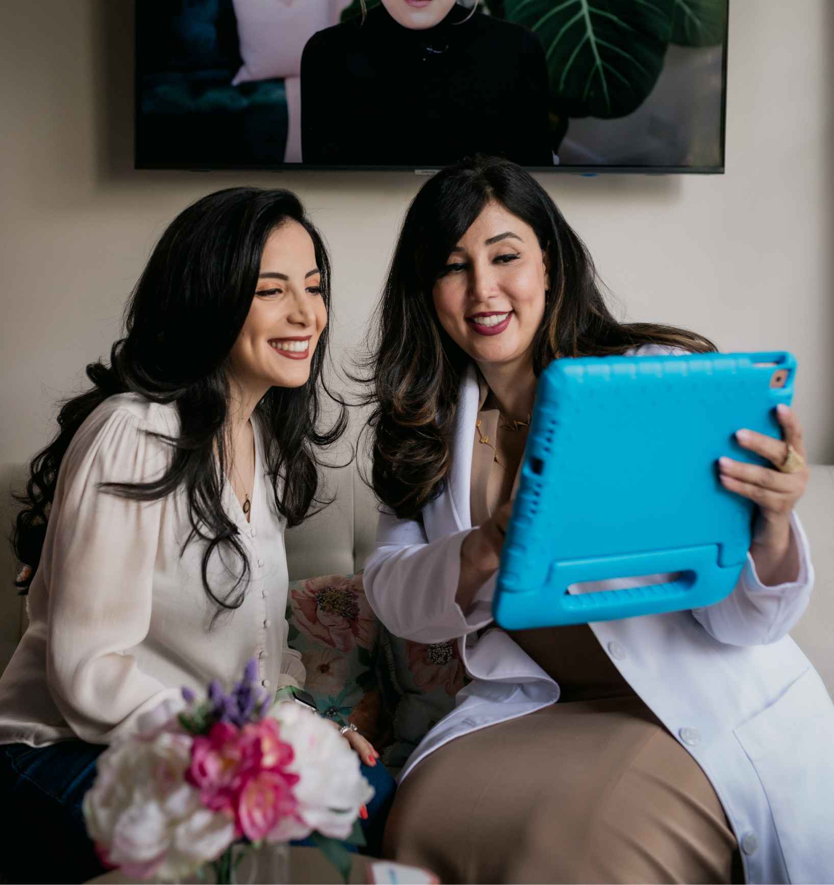 Photo of a dentist and patient smiling and looking at a tablet