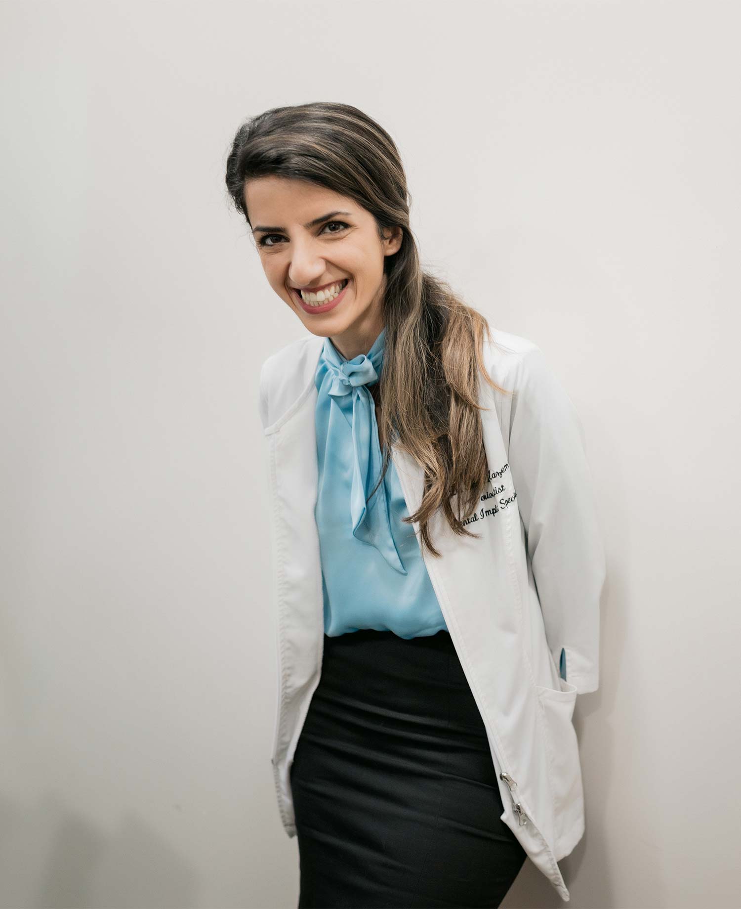 A smiling dentist wearing a white lab coat