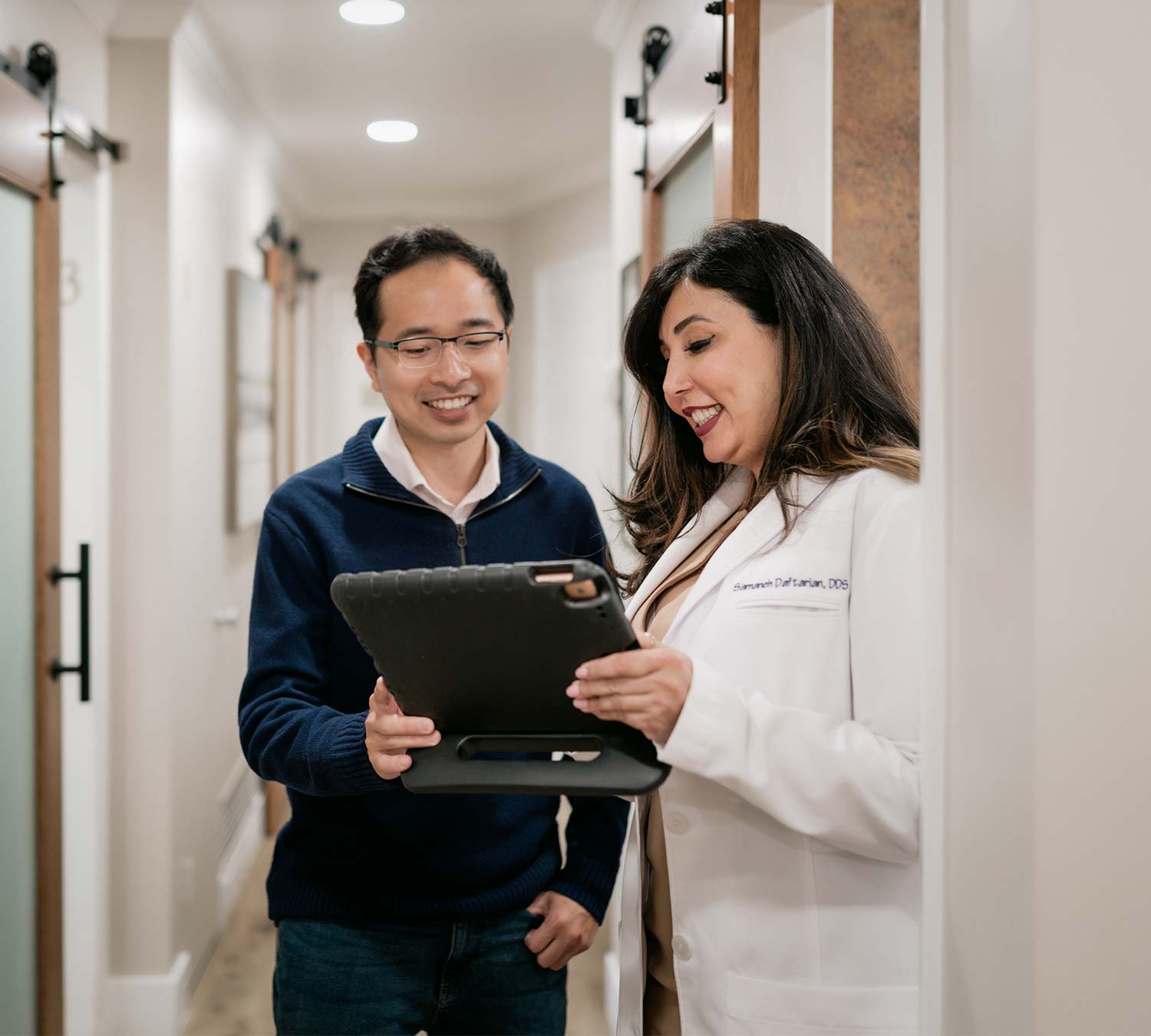 Dr. Daftarian holds an iPad so a patient can read the screen
