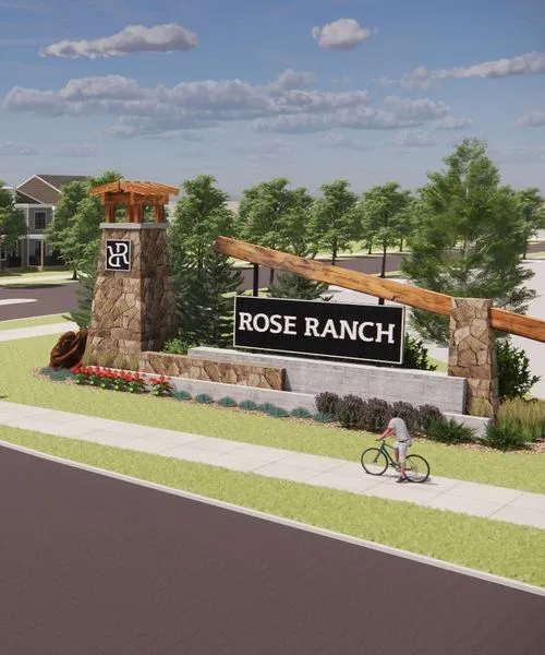 Stone and wood entrance sign for Rose Ranch with landscaping and a person riding a bicycle on the sidewalk.
