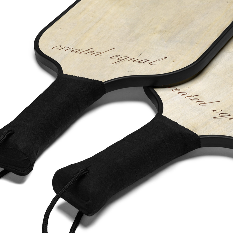 Game on! This pickleball set comes with 2 sturdy wooden paddles and 2 bright yellow balls, so you’re ready to rally in style. It includes a see-through bag made for beach trips, park days, or spontaneous matches—just grab it and go play!

• 100% wood paddles with black edges
• Soft poly-cotton handle grips for comfort
• Set includes 2 paddles, 2 plastic balls, and a carry bag
• Same design on both sides of each paddle
• Blank product sourced from China