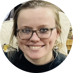 Smiling woman with glasses and light hair pulled back, wearing a black top.