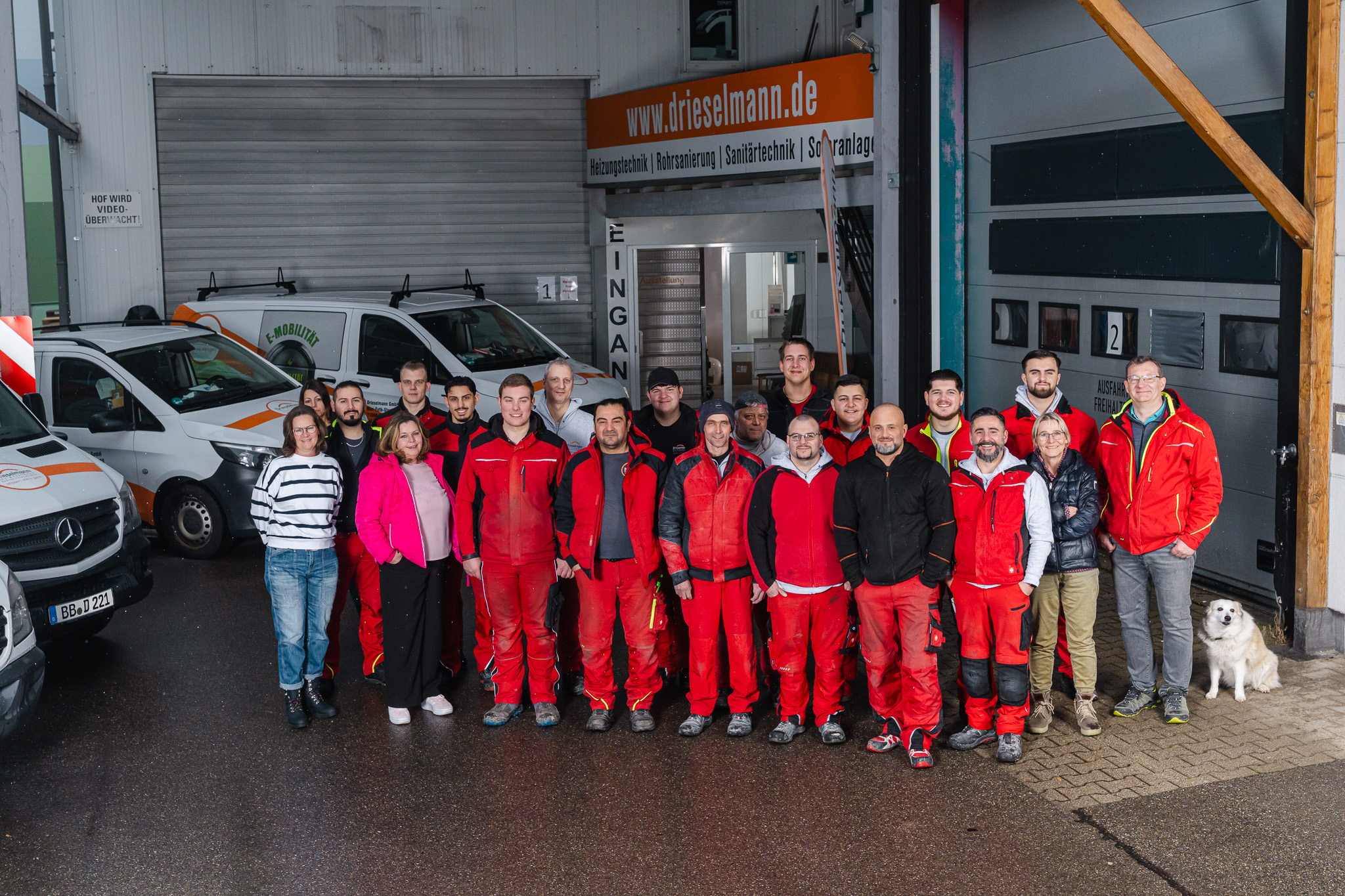 Team_Drieselmann in der Garage vor den Firmenwagen, die für ein Foto Posieren 