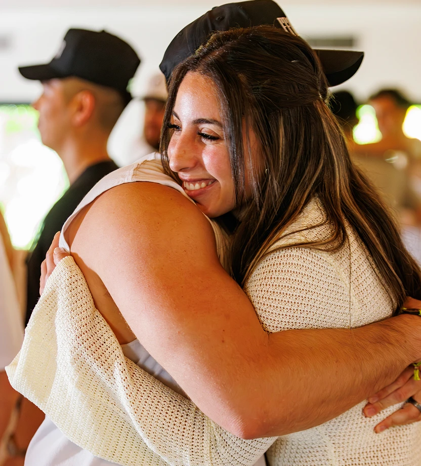 Three people sitting together at a wooden bar counter in a dimly lit setting, engaging in conversation.