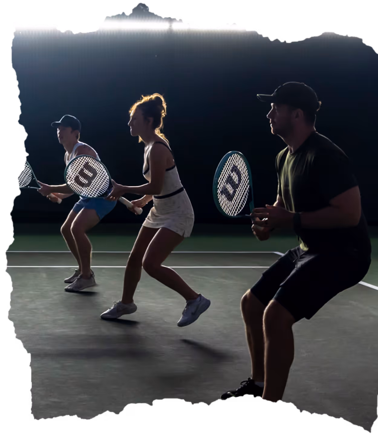 Group of young adults smiling and posing together outdoors at night under open canopies.