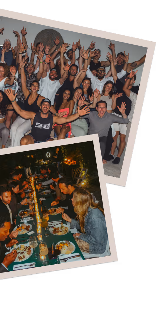 Outdoor dining area at dusk with string lights hanging above tables and chairs surrounded by palm trees.
