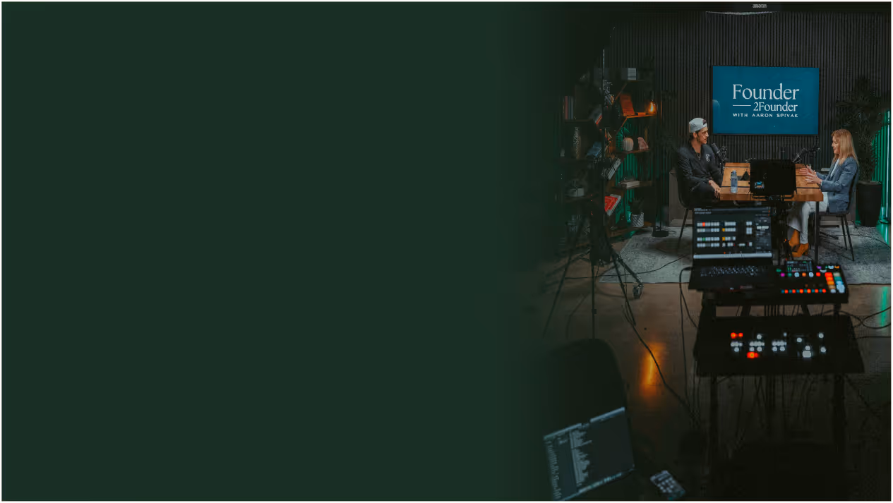 Two men smiling and posing, one in a suit and the other in a casual shirt, both wearing watches with a dark background featuring a logo.