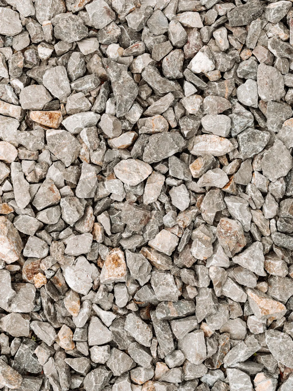 Close-up of gray and light brown crushed stones and gravel tightly packed together.