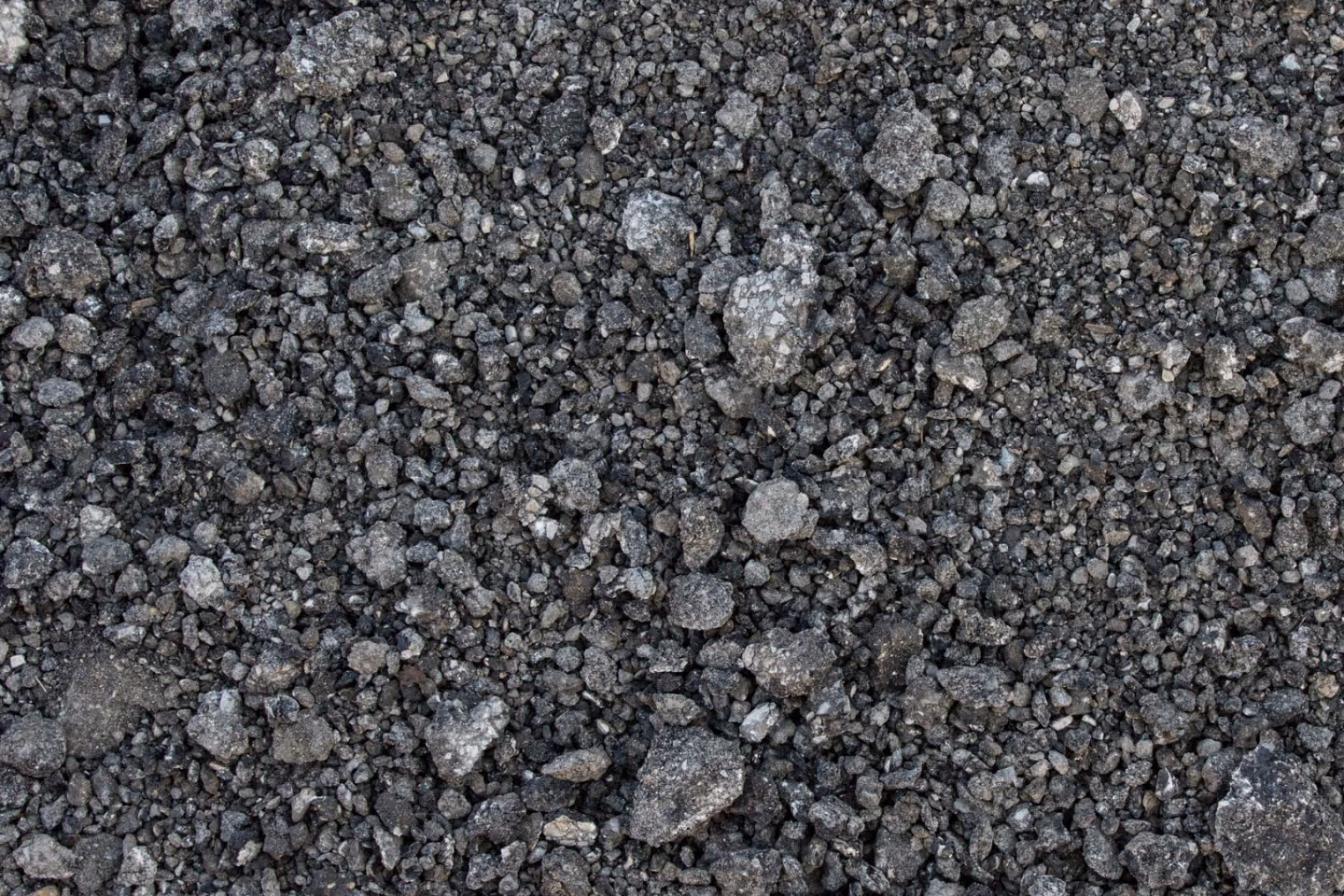 Close-up of a textured surface covered with small to medium-sized gray and black gravel stones.