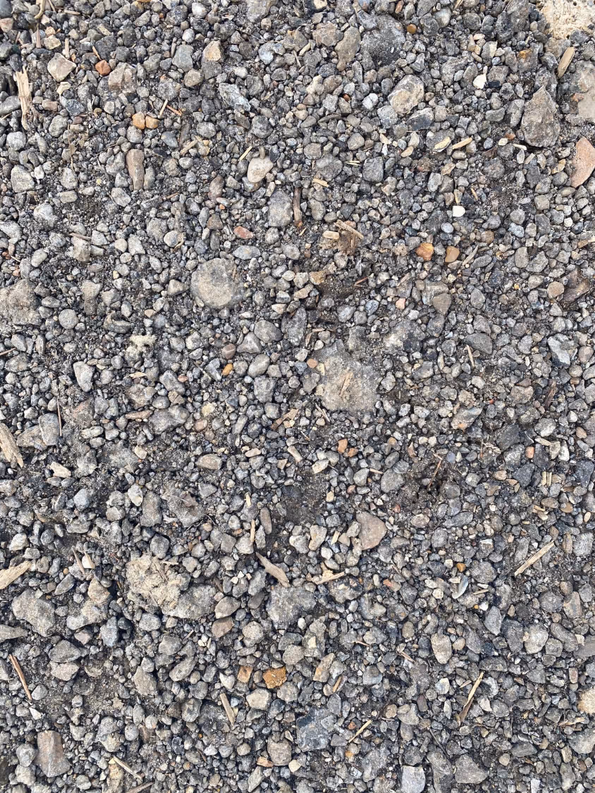 Close-up of small gray gravel stones with some scattered twigs.