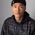 Young man wearing a dark beanie and a black checkered shirt against a white background.