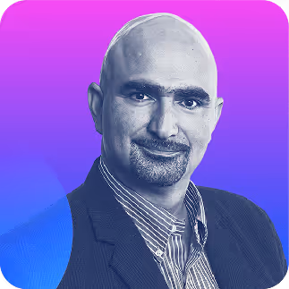 Portrait of a bald man with a goatee and mustache wearing a dark blazer and striped shirt against a purple to blue gradient background.