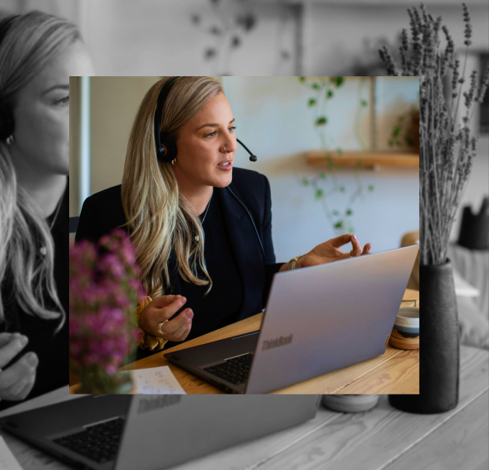 Kathleen sitting at a desk, talking with a headset on and a laptop in front of her.