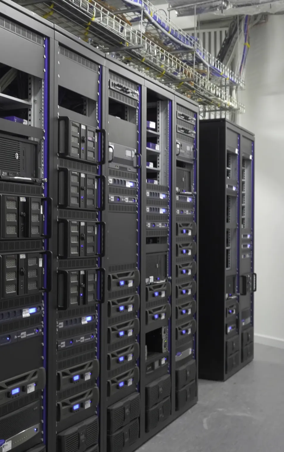 Row of black server racks with blue indicator lights in a data center room.