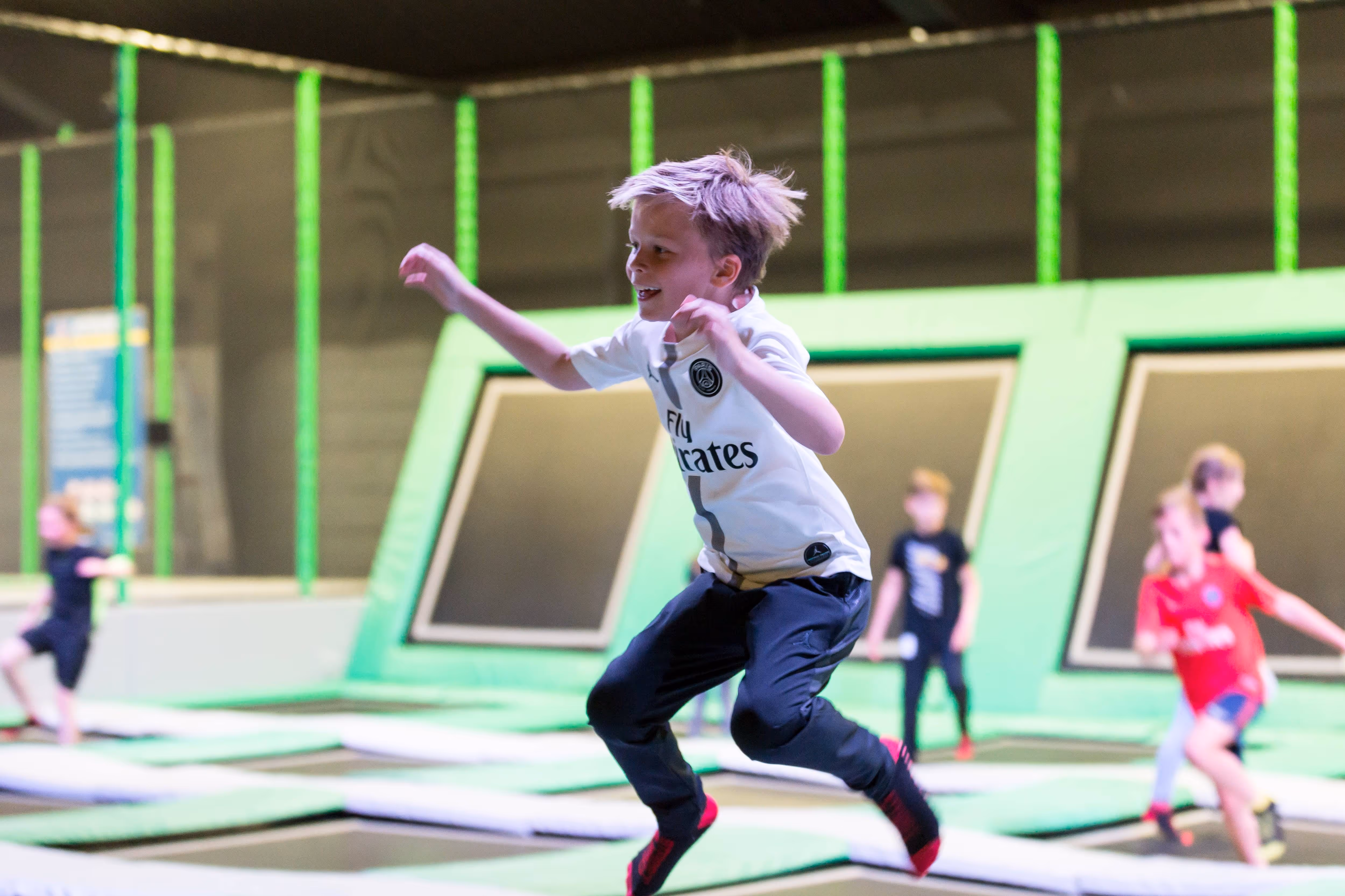 Kinderen springen en spelen tussen trampolines en luchtkussels in het airpark.