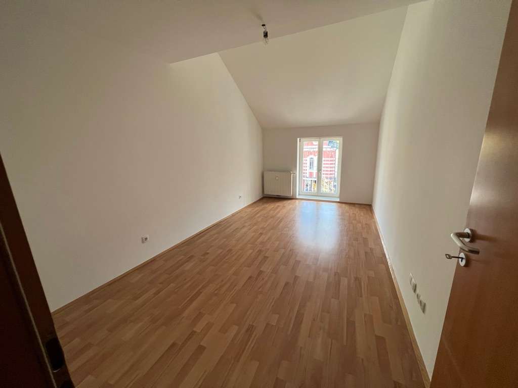 Helles Zimmer im Dachgeschoss mit schräger Decke, Fenster und Laminatboden