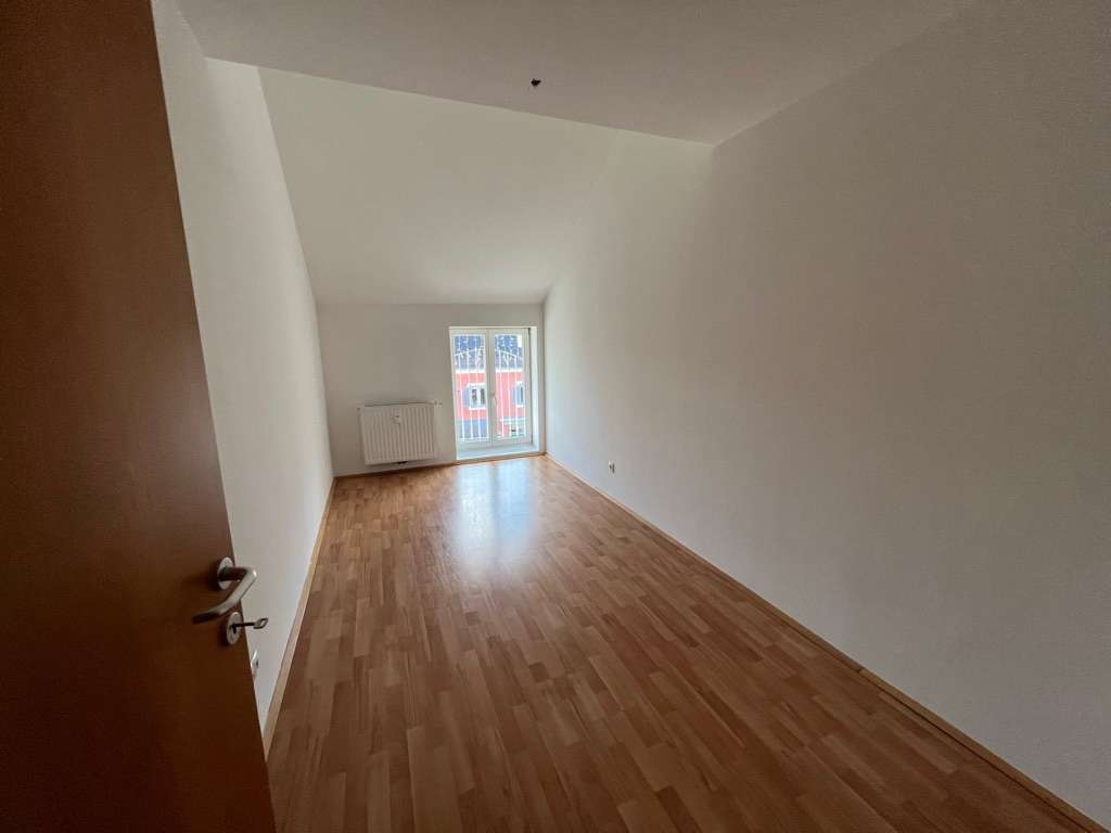 Schmales, lichtdurchflutetes Schlafzimmer mit Fenster und Laminatboden