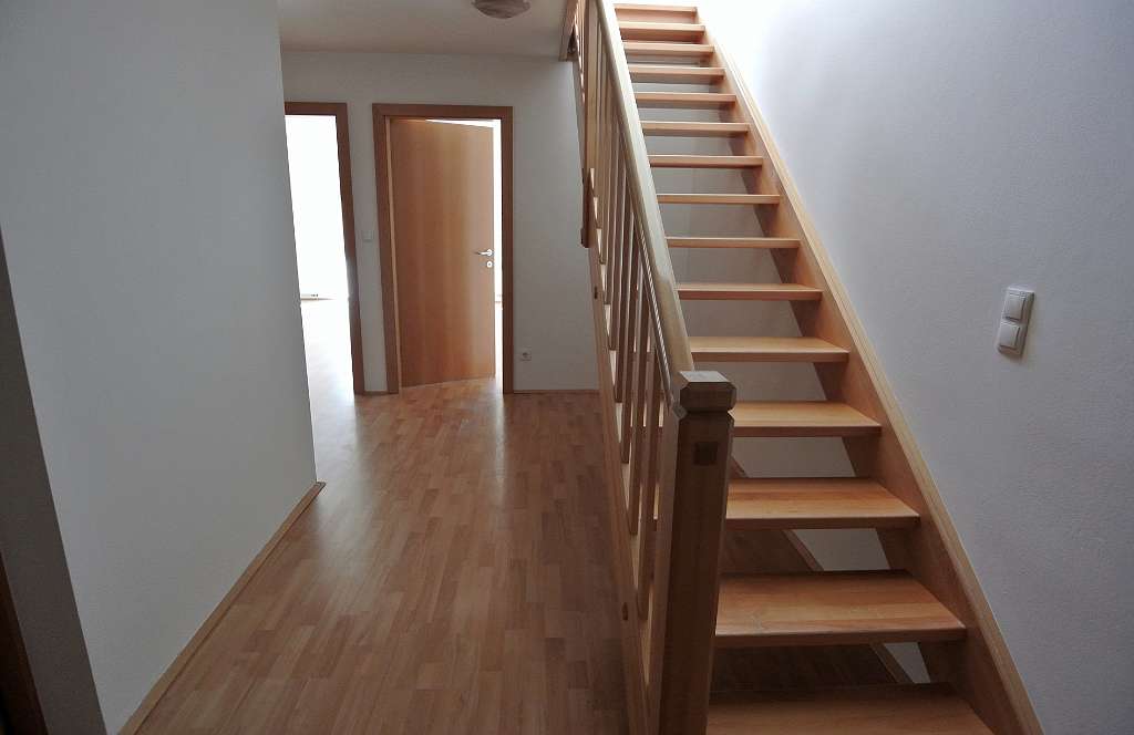 Innenbereich mit Holztreppe, Holzboden und zwei geöffneten Türen zu den Zimmern