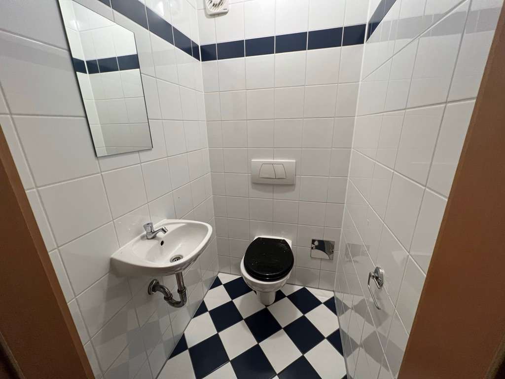Separates WC mit Wandwaschbecken und schwarz-weiß kariertem Boden