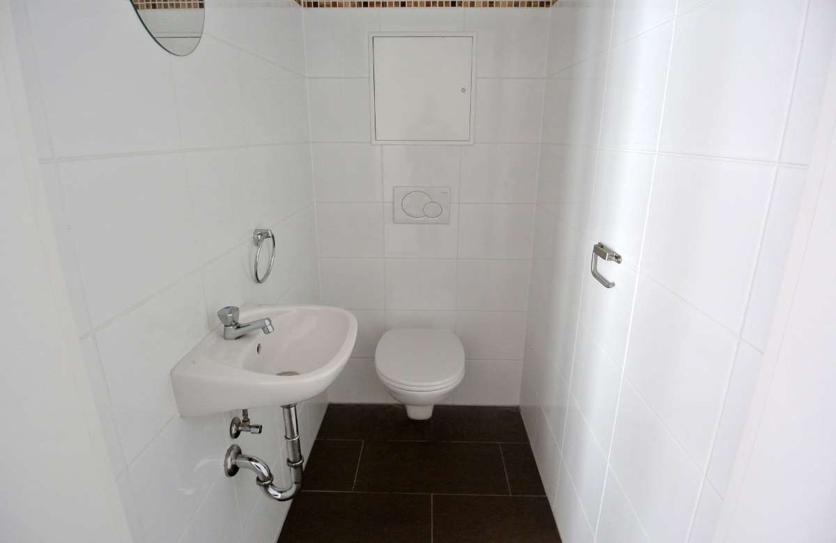 Kleines Badezimmer mit Waschbecken, WC und weißen Wandfliesen