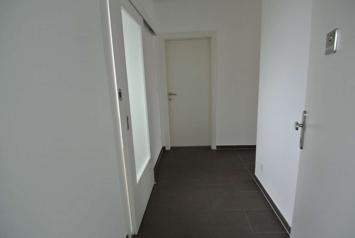 Schlichter weißer Flur mit dunklem Boden und zwei Zimmertüren