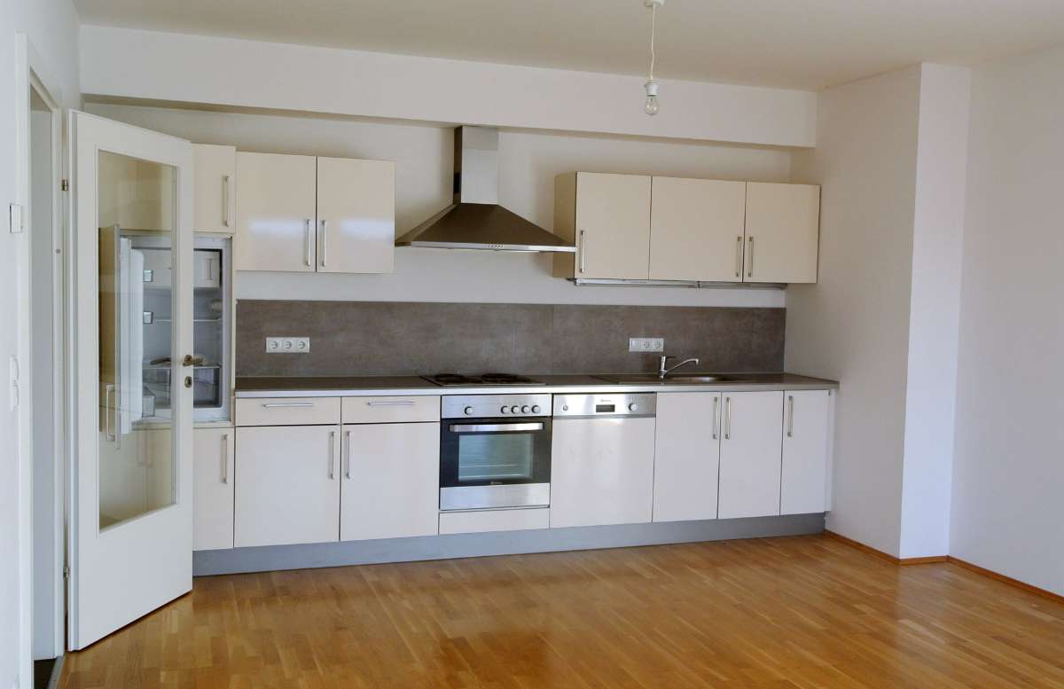 Einbauküche mit hellen Schränken, Edelstahlherd und Dunstabzugshaube