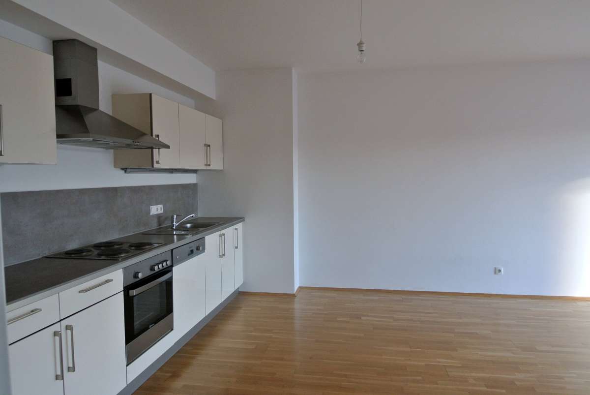 Moderne Einbauküche mit weißen Fronten, grauer Arbeitsplatte und Holzfußboden