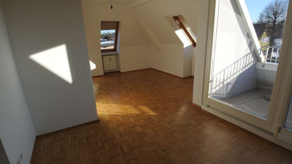 Wohnraum mit Dachschrägen, Parkettboden und Zugang zum Balkon