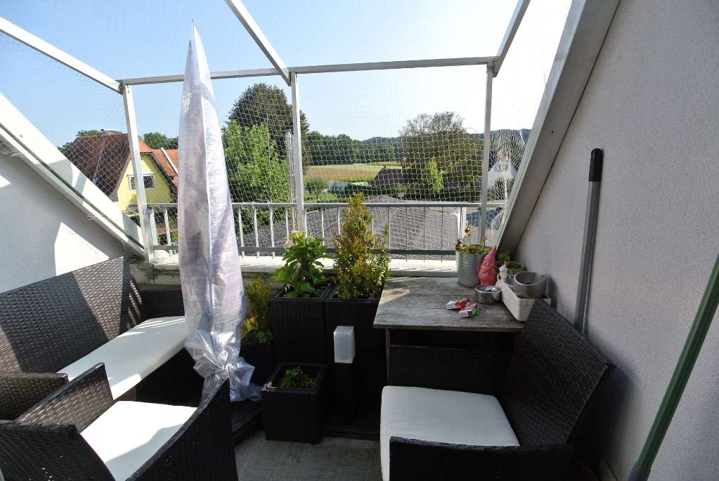 Kleiner Balkon mit Sitzlounge, Sonnenschirm und Blick auf die Umgebung