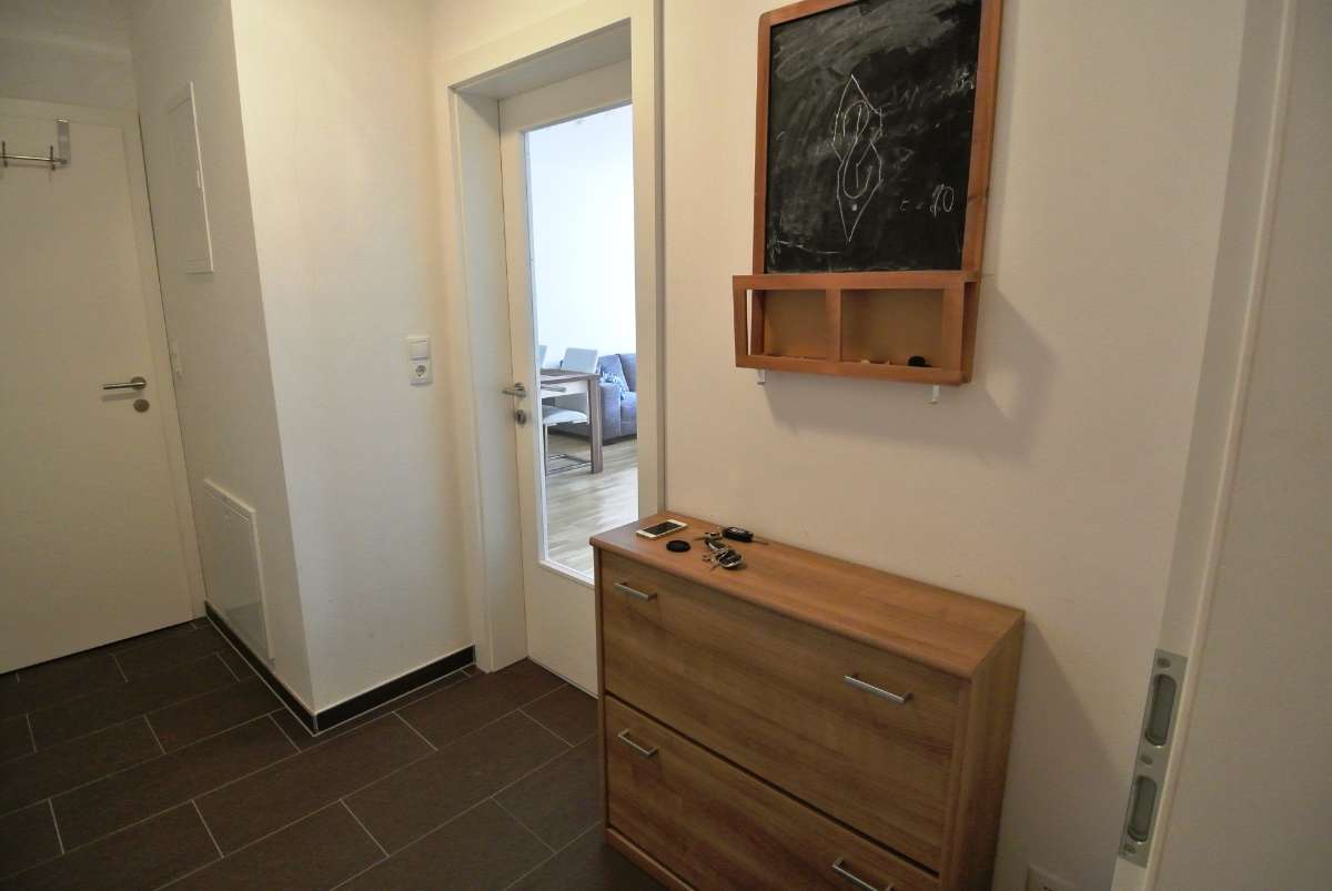 Flur mit Fliesenboden, Konsolentisch und Tür mit Glaseinsatz