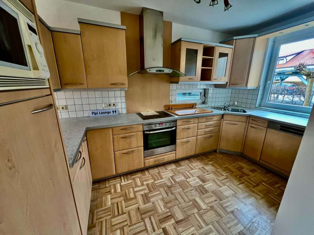 Einbauküche in L-Form mit Holzfronten, Parkettboden und großem Fenster